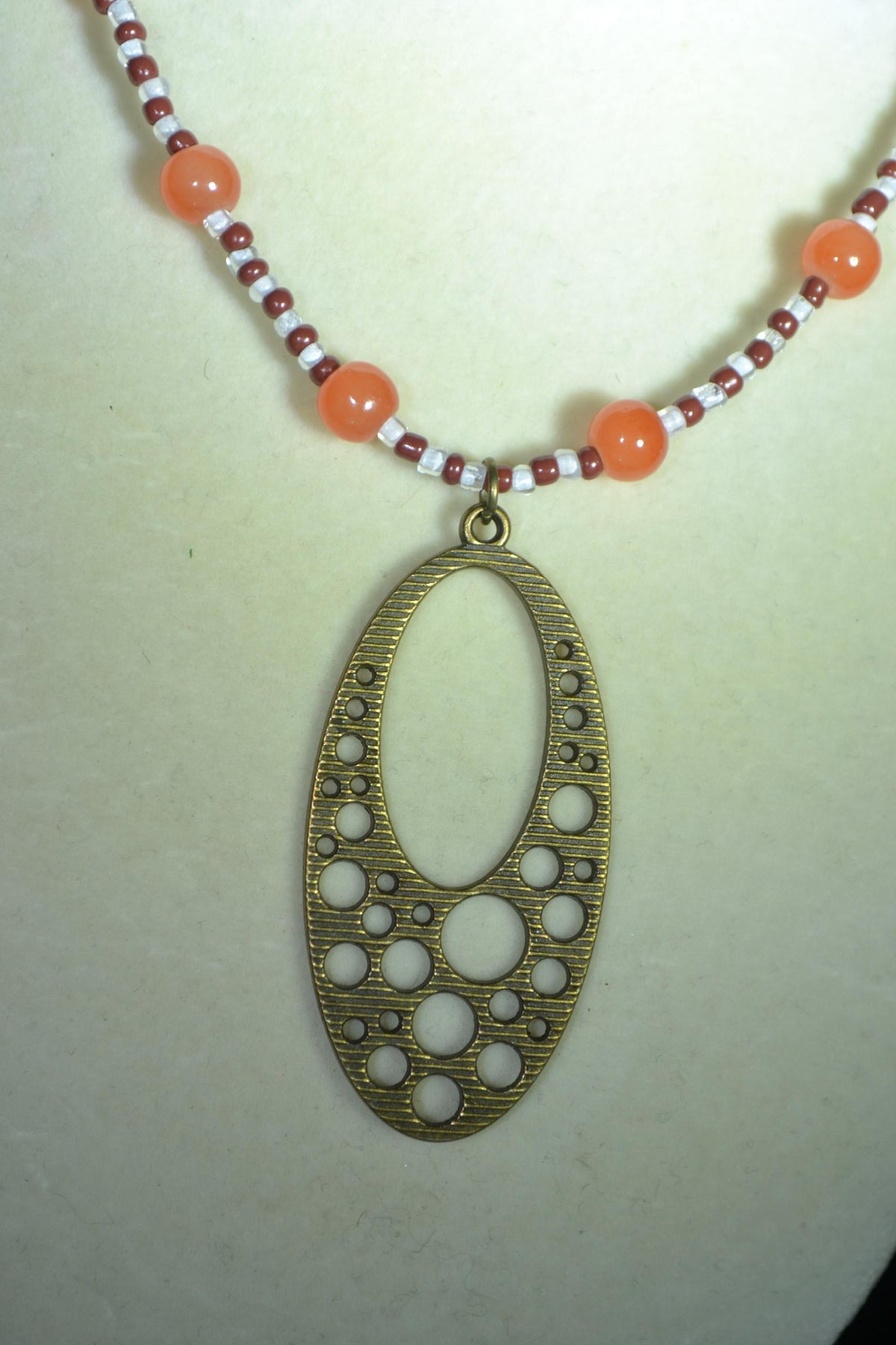 Brass bubbles pendant glass bead necklace. Orange, white, and brown