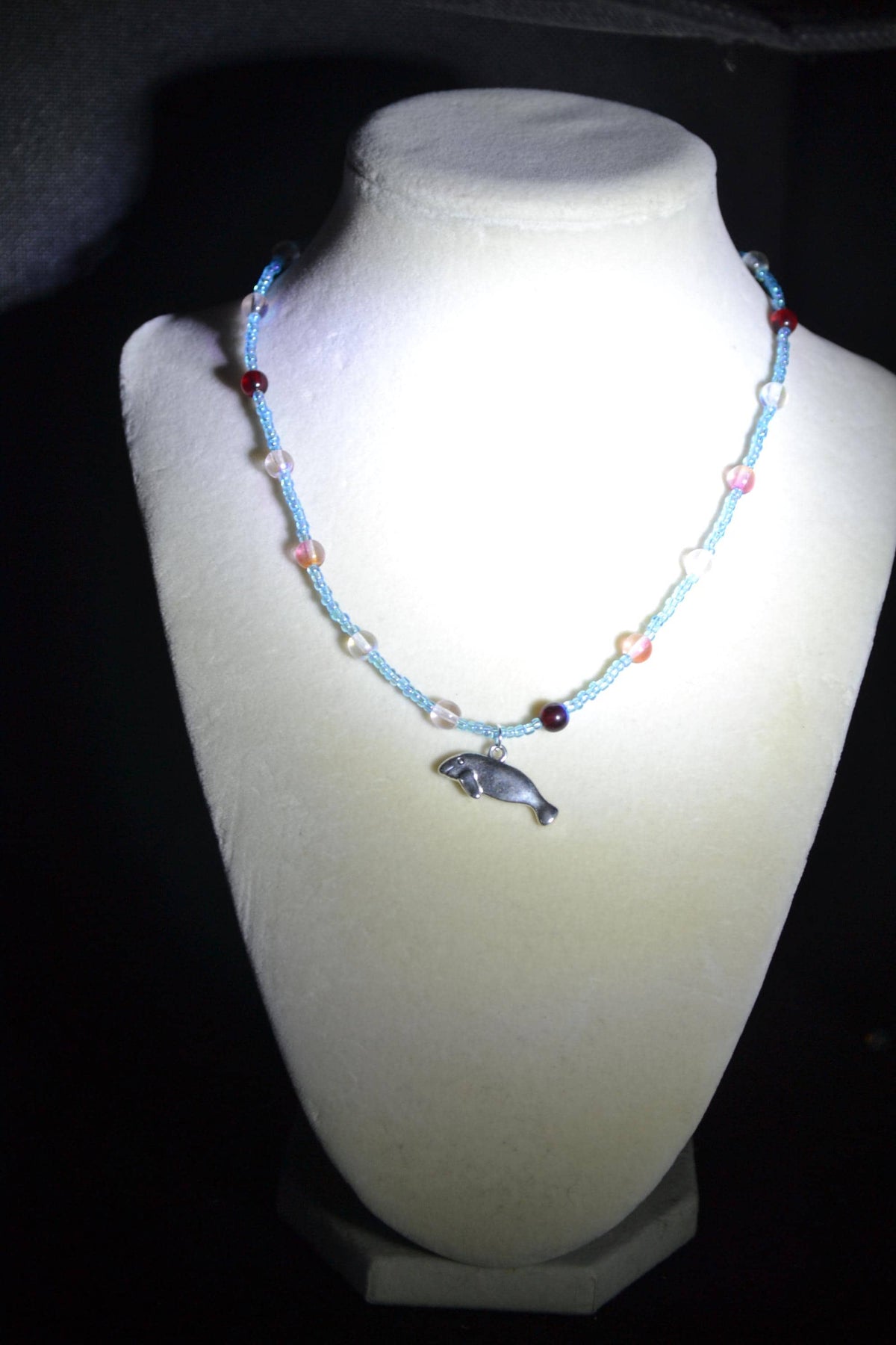 Silver Manatee pendant glass bead necklace. Blue and reds