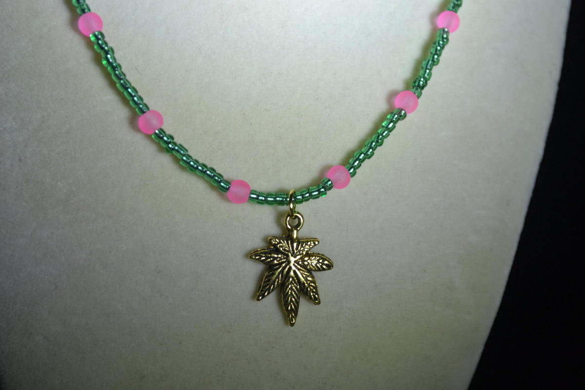 Gold Marijuana Leaf pendant glass bead necklace. Green and frosted pink