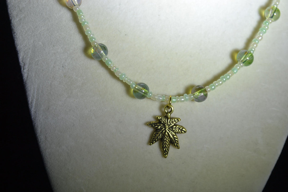Gold Marijuana Leaf pendant glass bead choker. Pearl white, green, and topaz