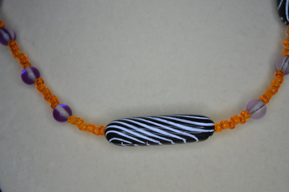 Multicolor glass and wood bead necklace. Orange, frosted purple, and black and white stripes