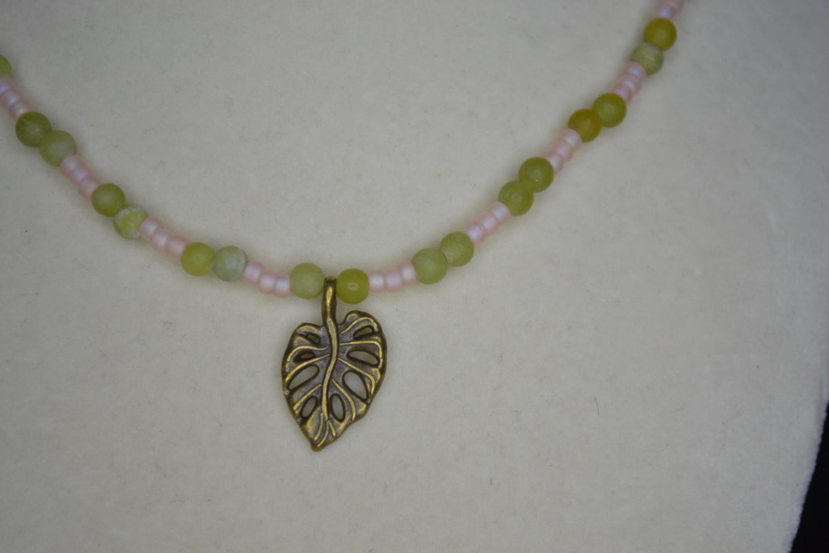 Bronze monstera pendant glass bead necklace. Jade and frosted pink