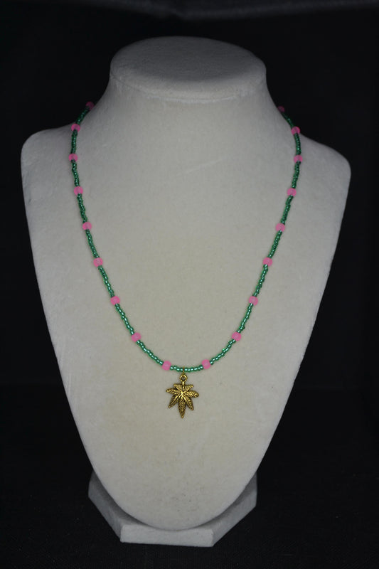 Gold Marijuana Leaf pendant glass bead necklace. Green and frosted pink