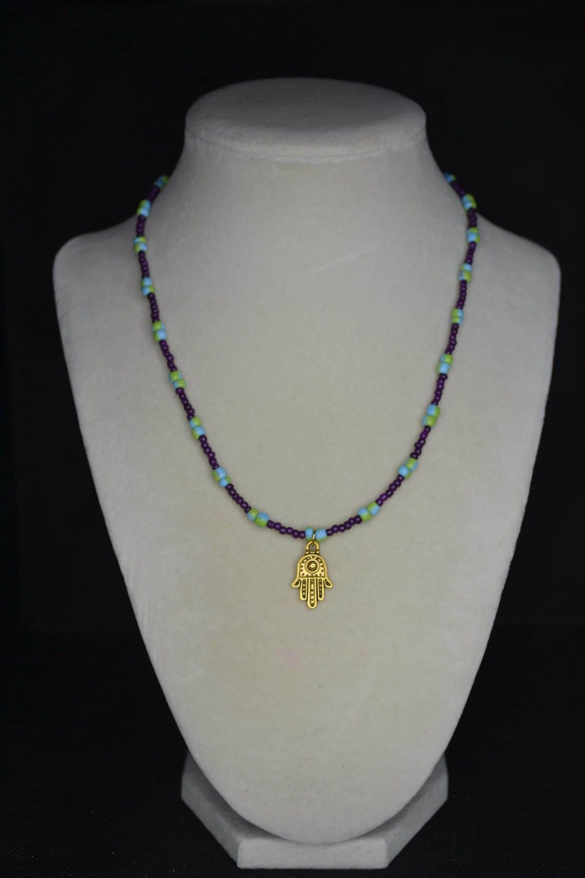 Gold Hamsa pendant glass bead necklace. Dark violet, blue, and green