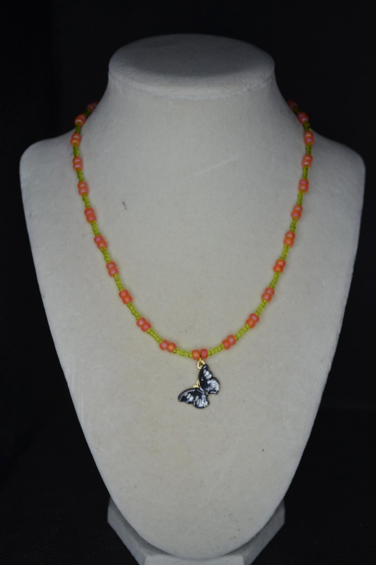 Black butterfly pendant glass bead necklace. Green and coral